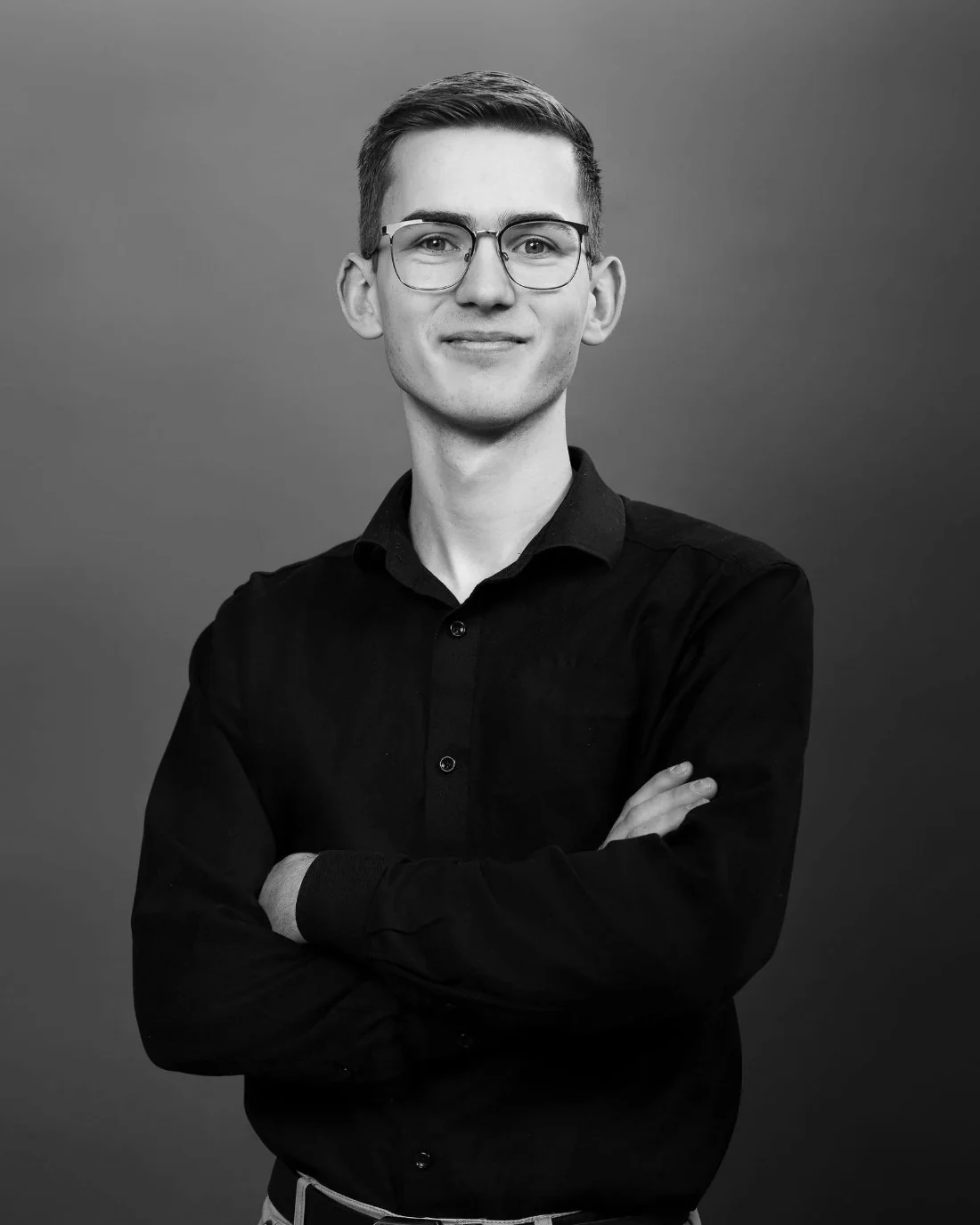 Josh Wiegman, arms crossed, in a black and white studio portrait